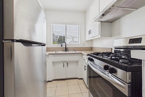 A modern kitchen with a stainless steel refrigerator, a stove, and a sink.