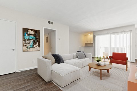 A living room with a white couch and a red chair.