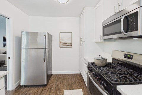 A kitchen with a stove, refrigerator, and microwave.