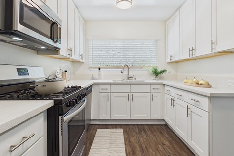 A kitchen with white cabinets and a black stove top.