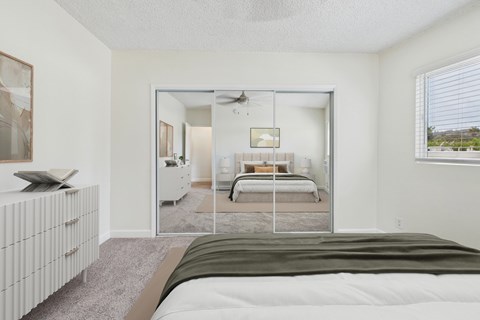 A bedroom with a large bed and a mirrored closet door.