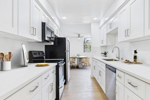 A modern kitchen with white cabinets and a black refrigerator.