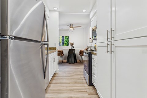 A modern kitchen with a stainless steel refrigerator and white cabinets.