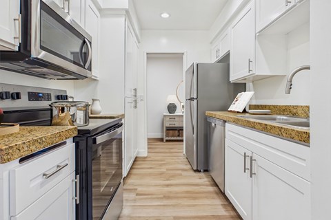 A kitchen with black and white appliances and wooden floors.