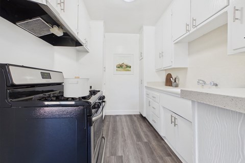 A kitchen with a black stove top oven and white cabinets.