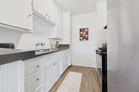 A kitchen with white cabinets and a black counter top.