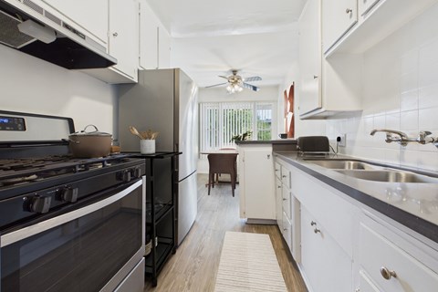 A modern kitchen with a black stove top oven and white cabinets.