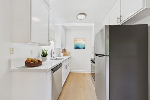 A kitchen with white cabinets and a black refrigerator.
