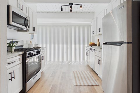 A modern kitchen with white cabinets and stainless steel appliances.