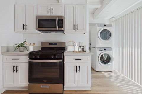A modern kitchen with a black stove top oven and white cabinets.
