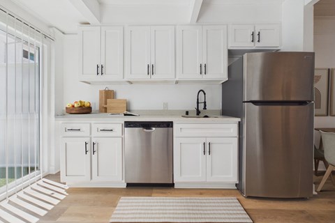 A modern kitchen with white cabinets and stainless steel appliances.
