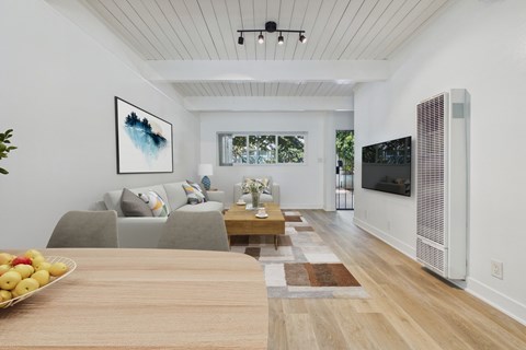 A modern living room with a grey couch, a wooden table, and a painting on the wall.
