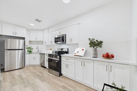 A kitchen with white cabinets and a wooden floor.