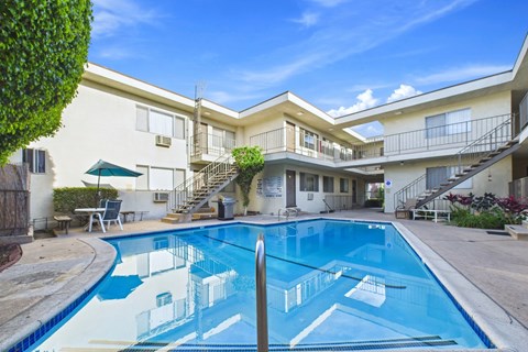 A swimming pool in front of a building with a blue sky in the background.