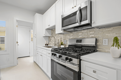 A modern kitchen with white cabinets and a black stove top.
