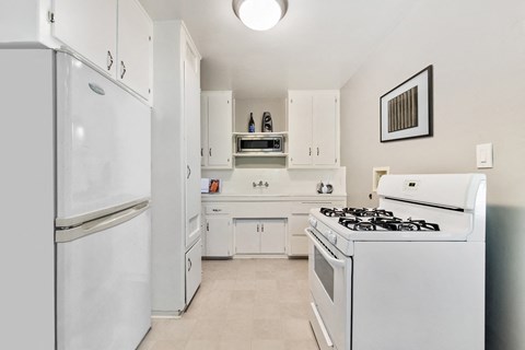 A white kitchen with a refrigerator, oven, and microwave.