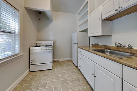 A white dishwasher is in a kitchen with white cabinets.