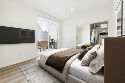 A bedroom with a large bed and a flat screen TV mounted on the wall.