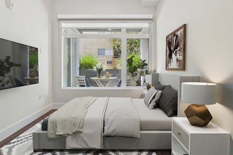 A modern bedroom with a large bed and a view of the outdoors.