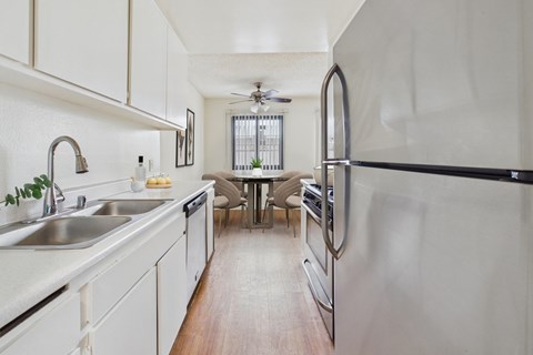 A modern kitchen with a stainless steel refrigerator and a dining table with chairs.
