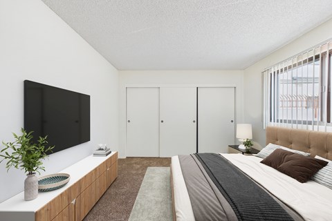 A bedroom with a large bed and a flat screen TV mounted on the wall.