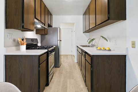 A kitchen with dark wood cabinets and a white stove top oven.
