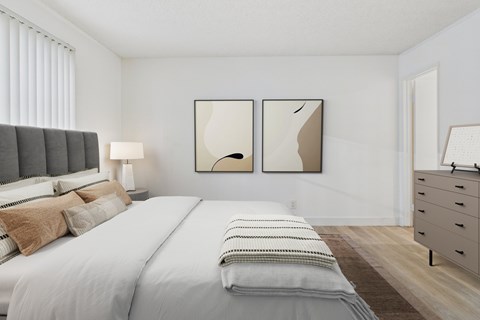 A bedroom with a large bed and two framed pictures on the wall.