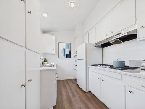 A kitchen with white cabinets and a wooden floor.