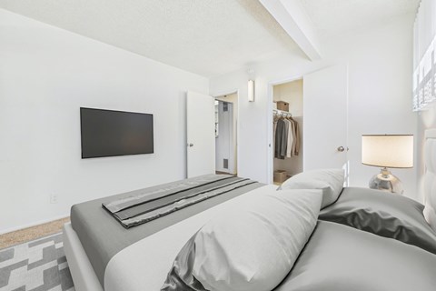 A bedroom with a large bed and a flat screen TV mounted on the wall.