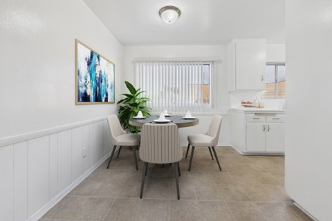 A dining room with a table set for two and a painting on the wall.