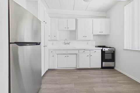 A kitchen with white cabinets and a stainless steel refrigerator.