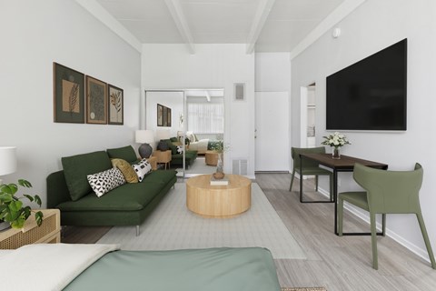 A living room with a green couch and a television on the wall.