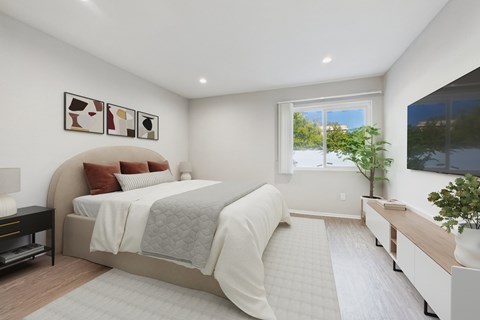A bedroom with a large bed and a window overlooking a tree.