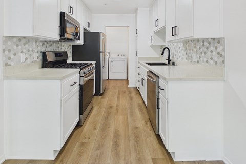 A kitchen with white cabinets and a black fridge.