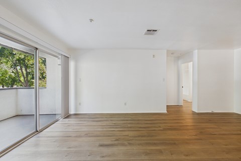 A spacious room with wooden floors and white walls.