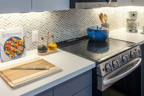 A kitchen counter with a Mediterranean cookbook, a blue bowl, and a wooden cutting board.