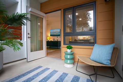 A chair with a blue pillow is in front of a window.
