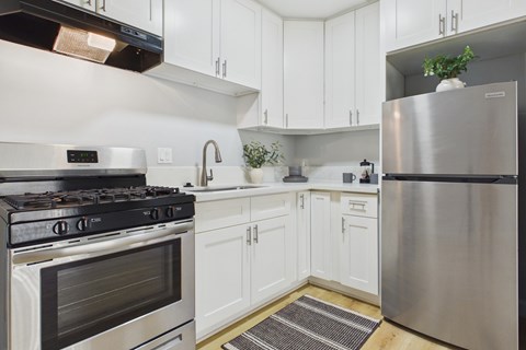 A modern kitchen with white cabinets and stainless steel appliances.
