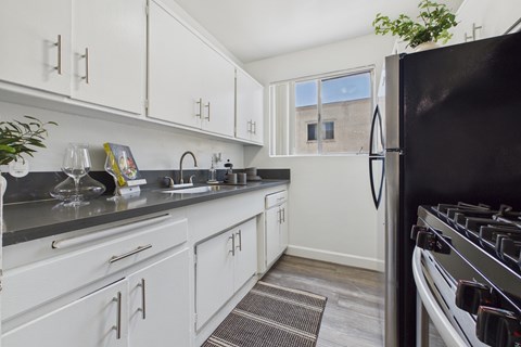 A kitchen with white cabinets and a black refrigerator.