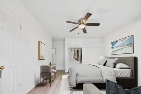 A bedroom with a bed, chair, and a ceiling fan.