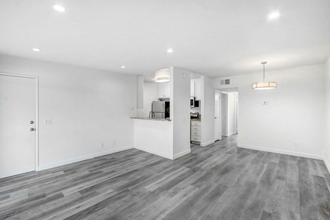 the living room and kitchen in a new home with white walls and wood flooring