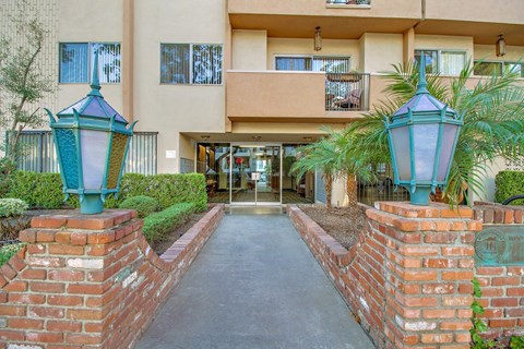A building entrance with a brick wall and two green lamps.