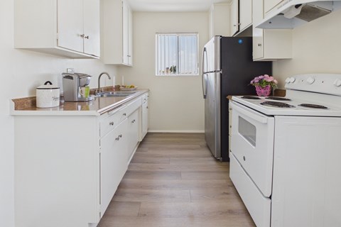 A kitchen with white appliances and wooden floors.