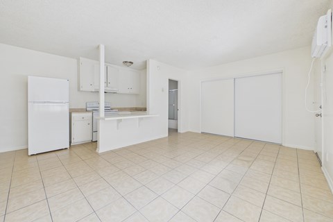 A white kitchen with a refrigerator, sink, and cabinets.