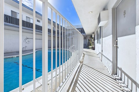 A white balcony with a pool and a white building in the background.