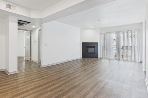 A spacious room with wooden flooring and white walls.
