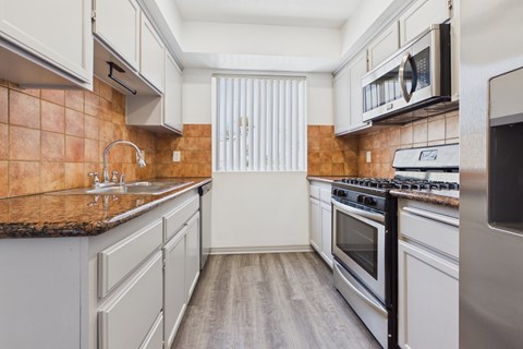 A kitchen with a brown counter top and white cabinets.