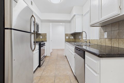 A kitchen with white cabinets and a black fridge.
