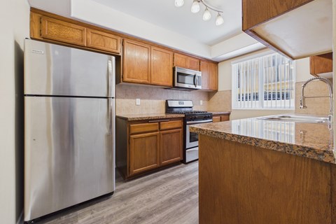 A kitchen with a stainless steel refrigerator and wooden cabinets.