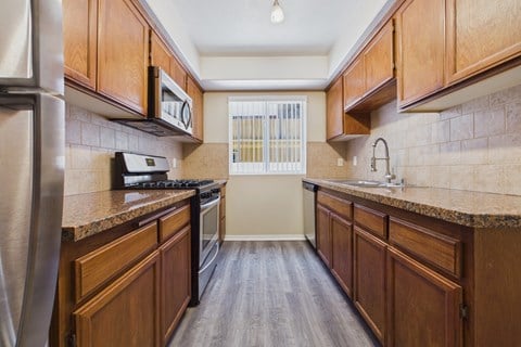 A kitchen with wooden cabinets and a stainless steel refrigerator.